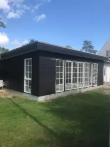 Færdig tilbygning med sort facade og store vinduespartier