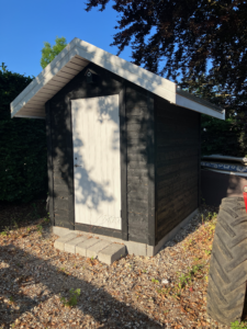 Moderne haveskur i sort træ med hvid dør