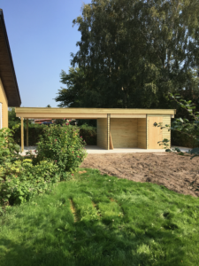 Færdig garagebygning i træ integreret i haven
