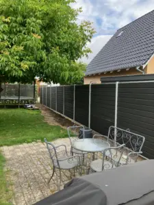 Komposithegn i haven, der skaber privatliv omkring terrasse og opholdsareal.