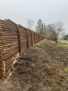 Naturhegn i rundstokke monteret langs skel i haveområde