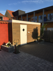 Haveskur med træbeklædning placeret i gårdmiljø