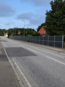 Langt støjhegn opsat langs befærdet vej for støjafskærmning af boliger