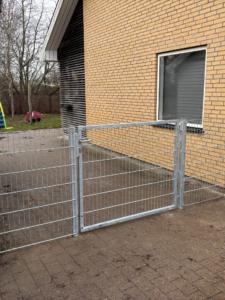 Panelhegn med låge opsat ved bolig for afskærmning og sikker adgang